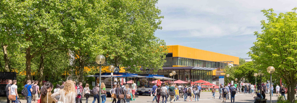 Campusleben mit Studierenden und Mensa Campusleben mit Studierenden und Mensa im Hintergrund